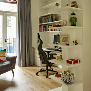 Medium sized contemporary study in London with white walls, light hardwood flooring, a freestanding desk and beige floors.