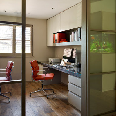 Trendy built-in desk dark wood floor study room photo in London with no fireplace