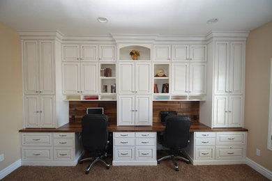 Modelo de despacho tradicional de tamaño medio sin chimenea con paredes beige, moqueta, escritorio empotrado y suelo beige