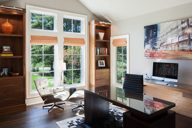На фото: кабинет среднего размера в современном стиле с серыми стенами, паркетным полом среднего тона, отдельно стоящим рабочим столом и коричневым полом без камина с