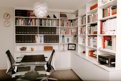 Example of a mid-sized minimalist medium tone wood floor study room design in Montreal with white walls