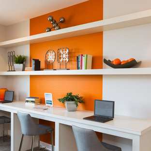 Klassisk inredning av ett hemmabibliotek, med orange väggar, ett inbyggt skrivbord och grått golv