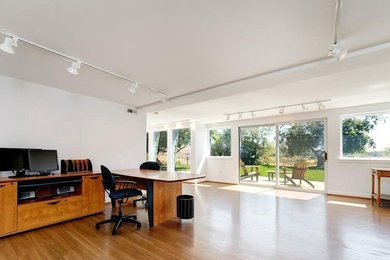ボイシにあるお手頃価格の広いミッドセンチュリースタイルのおしゃれなホームオフィス・書斎 (白い壁、自立型机、茶色い床) の写真