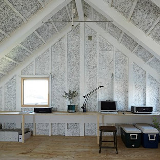 Exempel på ett mellanstort modernt hemmabibliotek, med ett inbyggt skrivbord, vita väggar och plywoodgolv