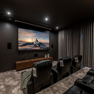 Modelo de cine en casa cerrado y negro, contemporáneo, con paredes negras, moqueta, pantalla de proyección y suelo gris