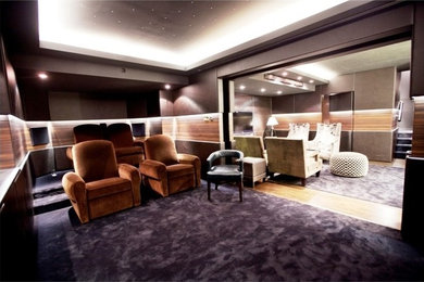 Large trendy enclosed carpeted home theater photo in Other with multicolored walls and a wall-mounted tv
