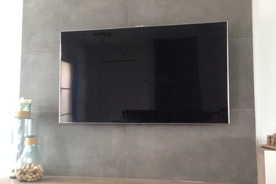 Diseño de cine en casa abierto moderno pequeño con paredes blancas, suelo de madera oscura y televisor colgado en la pared