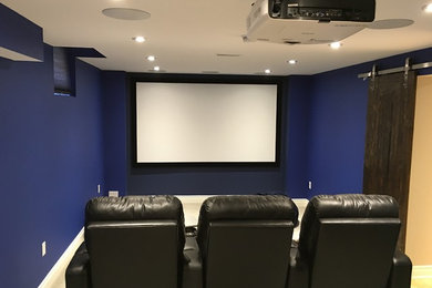 Réalisation d'une salle de cinéma tradition fermée avec un mur bleu, moquette et un écran de projection.