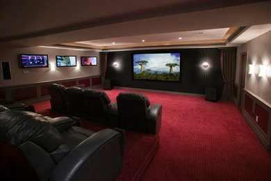 Example of a carpeted home theater design in Denver with beige walls and a projector screen