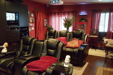 Exemple d'une grande salle de cinéma chic fermée avec un mur rouge, parquet foncé, un écran de projection et un sol marron.