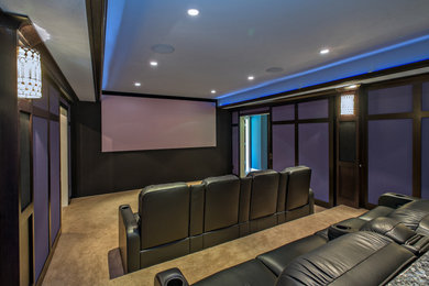 Diseño de cine en casa cerrado de estilo americano grande con paredes azules, moqueta y pantalla de proyección