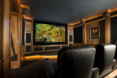 Modelo de cine en casa cerrado tradicional de tamaño medio con paredes marrones, moqueta y pantalla de proyección