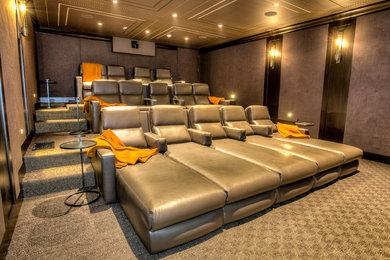 Example of a large trendy carpeted and brown floor home theater design in Los Angeles with brown walls and a media wall