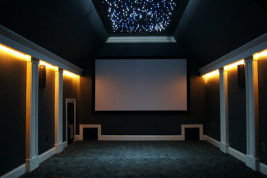 Immagine di un home theatre minimalista di medie dimensioni e chiuso con pareti grigie, moquette e schermo di proiezione