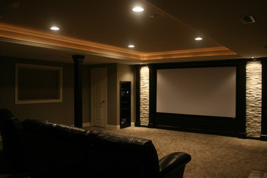 Modelo de cine en casa abierto actual de tamaño medio con paredes grises, moqueta y pantalla de proyección