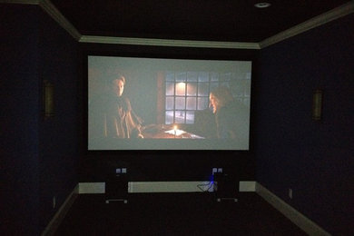 Ejemplo de cine en casa cerrado moderno extra grande con paredes negras, moqueta, pantalla de proyección y suelo negro