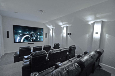Modelo de cine en casa cerrado moderno con paredes blancas, moqueta y televisor colgado en la pared