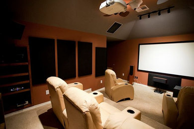 Ejemplo de cine en casa cerrado clásico con parades naranjas, moqueta y pantalla de proyección