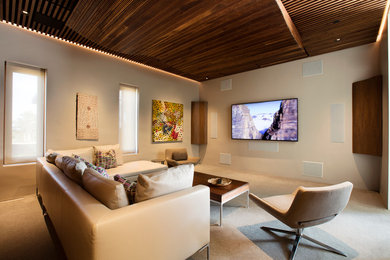 Modelo de cine en casa cerrado contemporáneo con paredes blancas, moqueta y televisor colgado en la pared