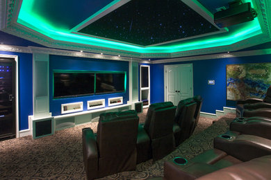 Cette image montre une petite salle de cinéma minimaliste fermée avec un mur bleu, moquette et un écran de projection.