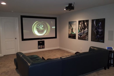Home theater - mid-sized modern enclosed carpeted and gray floor home theater idea in Raleigh with gray walls and a projector screen