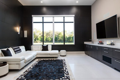 Imagen de cine en casa cerrado minimalista grande con paredes negras, suelo de piedra caliza, televisor colgado en la pared y suelo blanco