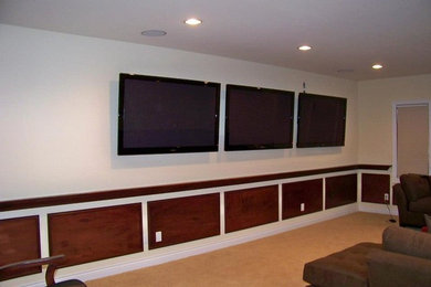 Modelo de cine en casa cerrado clásico de tamaño medio con paredes beige, televisor colgado en la pared, moqueta y suelo beige