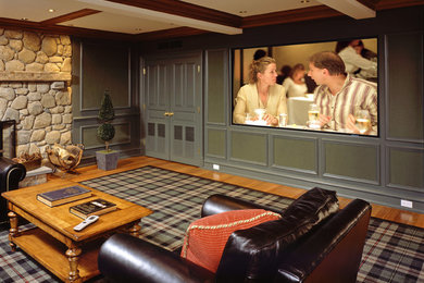 Modelo de cine en casa cerrado clásico grande con paredes verdes, suelo de madera en tonos medios, pantalla de proyección y suelo marrón