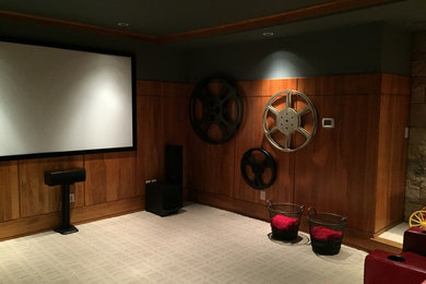 Example of a large mountain style enclosed carpeted and beige floor home theater design in Atlanta with brown walls and a projector screen