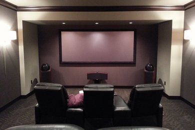 Modelo de cine en casa cerrado tradicional de tamaño medio con paredes grises, moqueta y pantalla de proyección