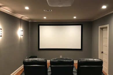 Inspiration for a mid-sized timeless enclosed medium tone wood floor and brown floor home theater remodel in Atlanta with beige walls and a projector screen