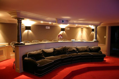Cette photo montre une salle de cinéma tendance de taille moyenne et fermée avec un mur beige, moquette, un écran de projection et un sol rouge.