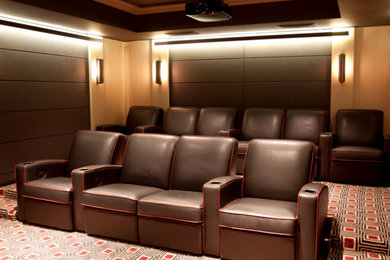 На фото: большой изолированный домашний кинотеатр в современном стиле с бежевыми стенами, ковровым покрытием, проектором и разноцветным полом