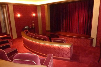 Diseño de cine en casa cerrado bohemio extra grande con paredes rojas, moqueta, pantalla de proyección y suelo rojo