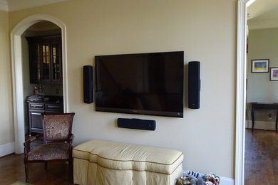 Example of a minimalist medium tone wood floor home theater design in Other with a wall-mounted tv
