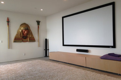 Imagen de cine en casa cerrado actual grande con paredes blancas, suelo de cemento, pantalla de proyección y suelo gris