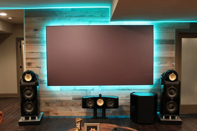 Inspiration for a timeless dark wood floor home theater remodel in Detroit with a projector screen