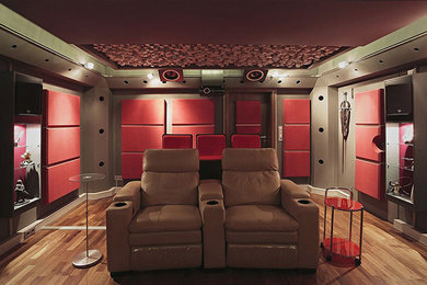 Modelo de cine en casa cerrado minimalista de tamaño medio con paredes rojas, suelo de madera clara, pantalla de proyección y suelo marrón