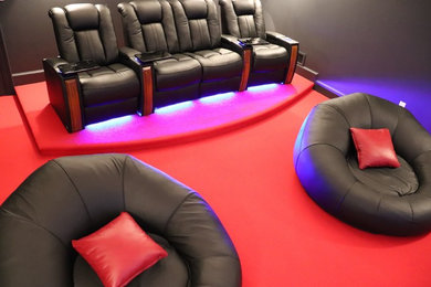Example of a mid-sized trendy enclosed carpeted and red floor home theater design in Boston with black walls and a projector screen