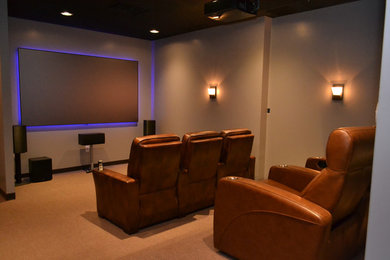 Inspiration for a mid-sized modern enclosed carpeted home theater remodel in Philadelphia with beige walls and a projector screen