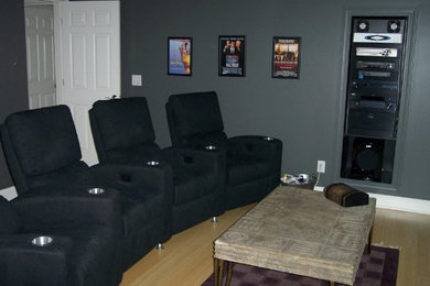 Example of a mid-sized classic enclosed light wood floor and beige floor home theater design in Raleigh with gray walls
