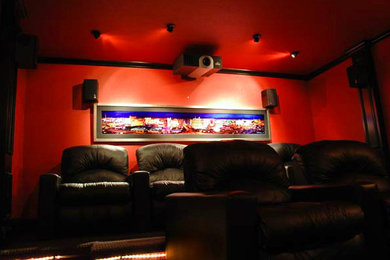 This is an example of a medium sized enclosed home cinema in Dallas with red walls and a projector screen.