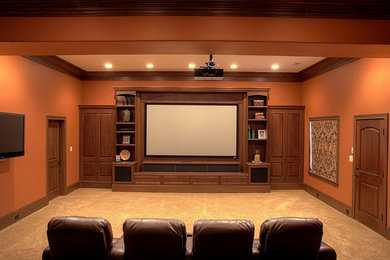 Large elegant enclosed carpeted and beige floor home theater photo in Other with orange walls and a projector screen