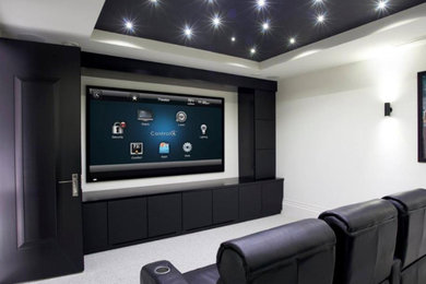 Diseño de cine en casa cerrado contemporáneo grande con paredes blancas, moqueta, televisor colgado en la pared y suelo gris