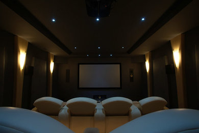 Ejemplo de cine en casa cerrado minimalista grande con paredes beige y pantalla de proyección