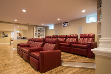 Home theater - large modern open concept light wood floor home theater idea in New York with beige walls and a media wall