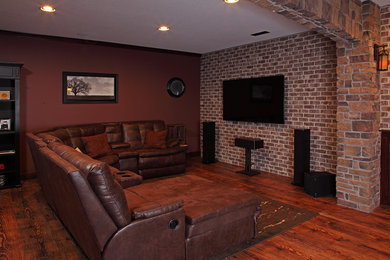 Ejemplo de cine en casa abierto rústico de tamaño medio con paredes marrones, suelo de madera en tonos medios, televisor colgado en la pared y suelo marrón