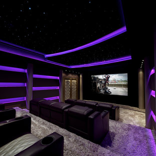 Cette photo montre une grand salle de cinéma tendance fermée avec un mur noir, moquette, un téléviseur encastré et un sol beige.