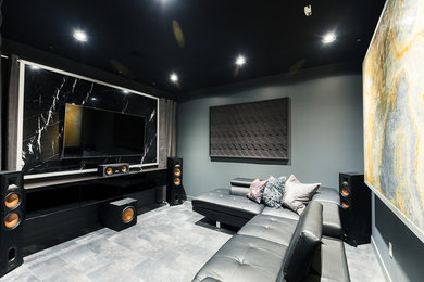 Ejemplo de cine en casa moderno de tamaño medio con paredes negras, suelo laminado, televisor colgado en la pared y suelo negro