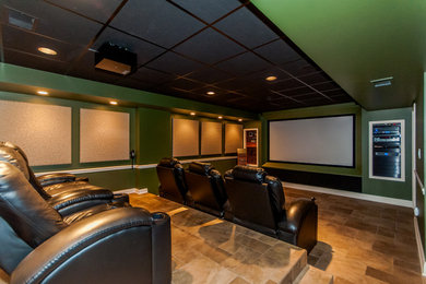 Modelo de cine en casa abierto contemporáneo con paredes verdes, suelo de baldosas de terracota, pantalla de proyección y suelo gris